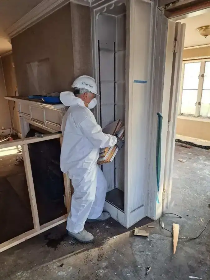 Technician restoring built in cabinetry and a fireplace surround in a home interior