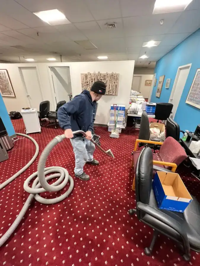 Clean Care technician running a carpet extraction hose across a flooded commercial office floor