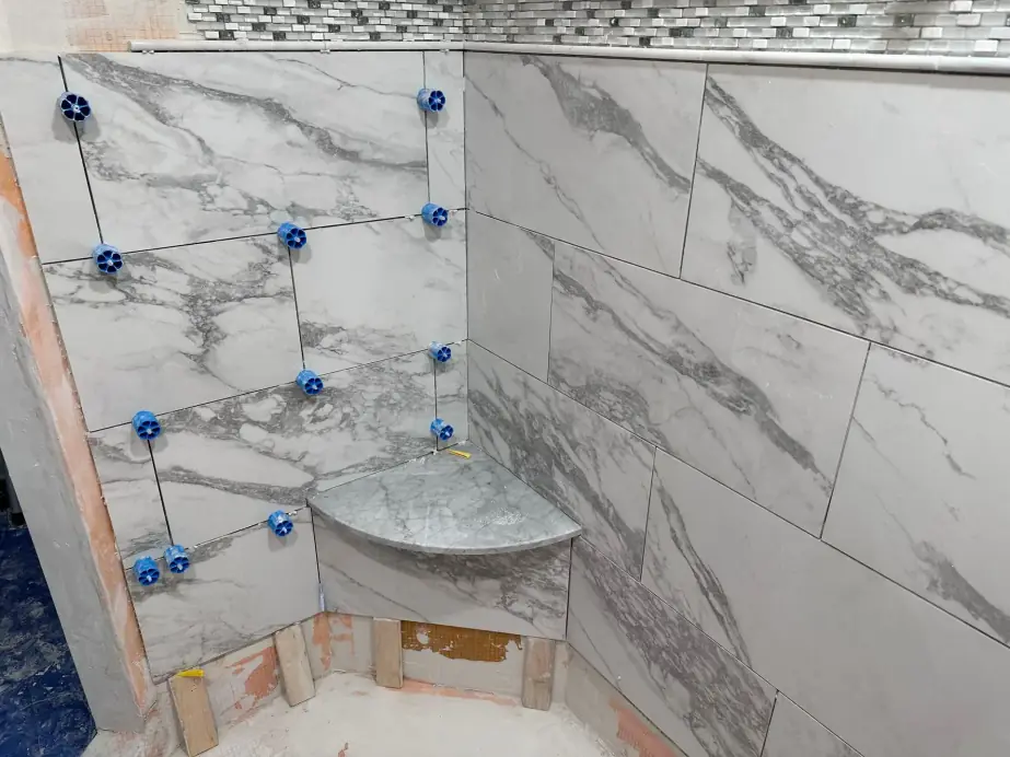 Finished custom marble tile shower with a corner bench