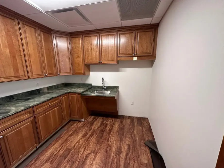 Finished commercial kitchenette with wood cabinets and a green stone countertop